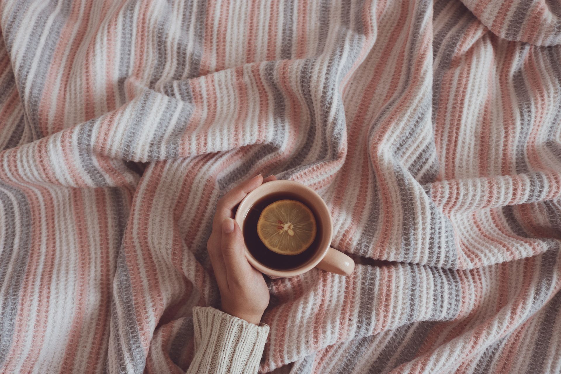 Close-up of a soft striped blanket with a warm cup of tea