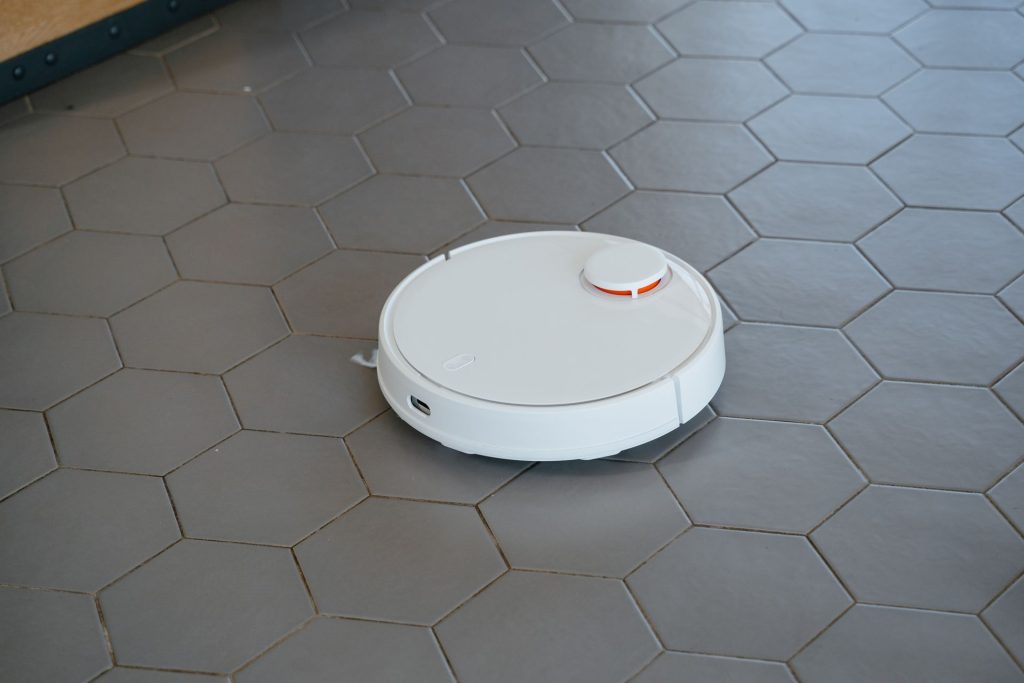 White robot vacuum cleaner cleaning a hexagonal tiled floor