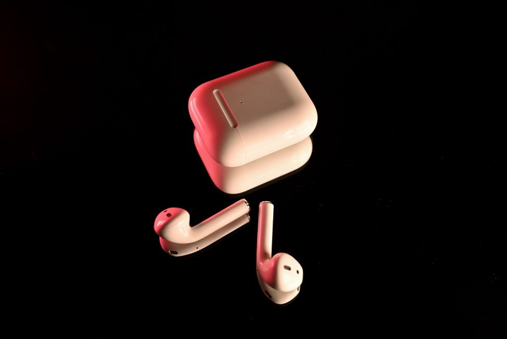 White wireless earbuds with their charging case on a black background