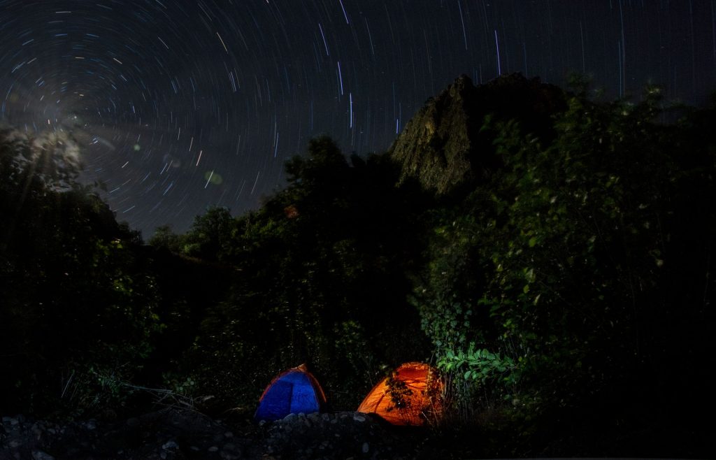 Tents under a starry night sky with star trails