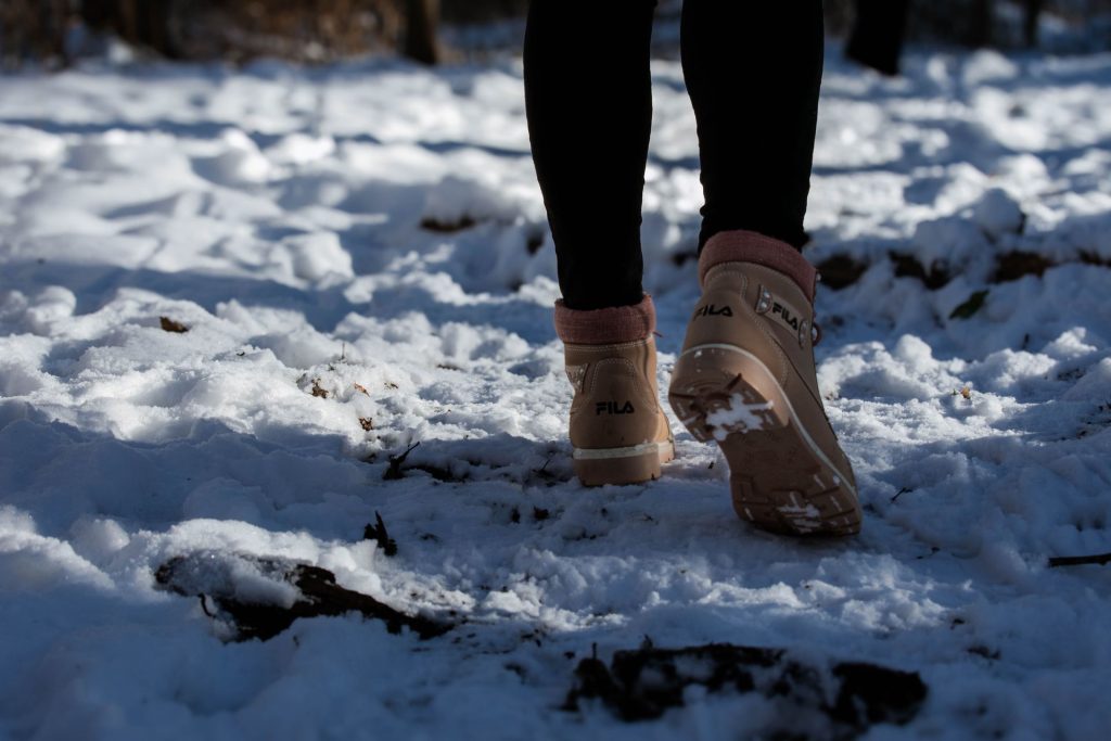 Brown boots walking a snow-covered forest path