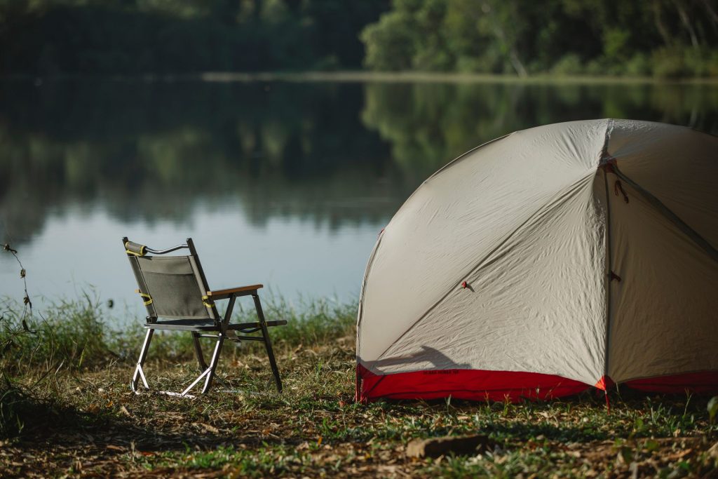 Folding camp chair beside a tent on a lakeshore